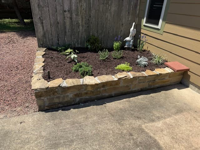Completed raised stone flower bed with new plantings Louisiana