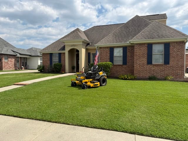 Zero-turn mower in front of brick home with American flag