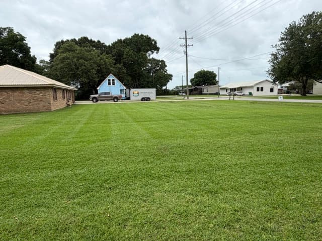 Freshly striped large lawn with work truck and trailer Louisiana